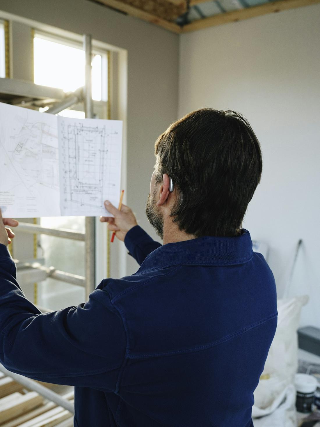 A man reading building plans in a house under renovation