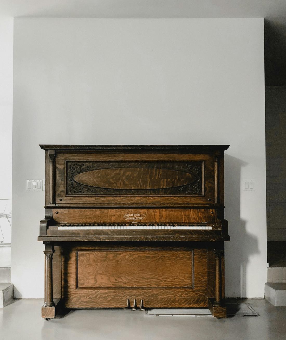 An old wooden upright piano against a white wall